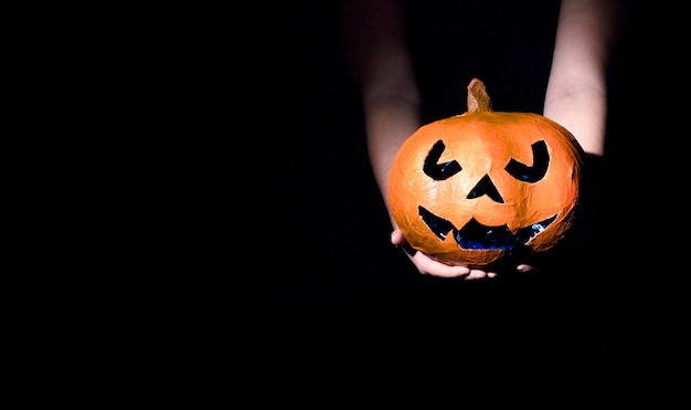 Free Photo hands holding decorative halloween pumpkin with carved face 