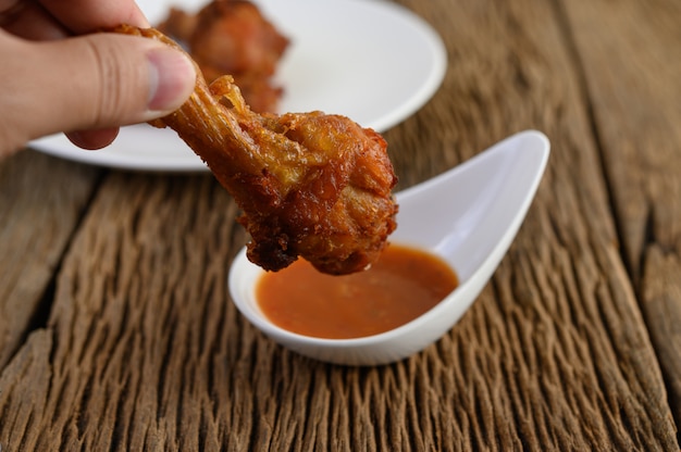 Hands holding fried chicken with sauce