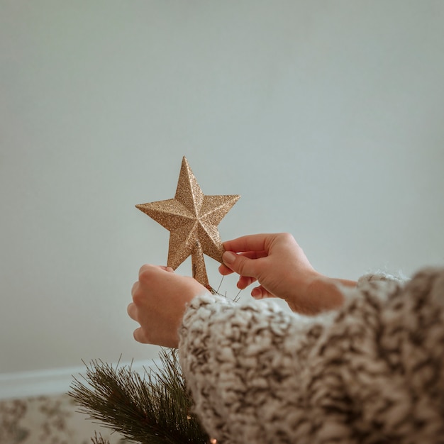 Hands holding golden top star for Christmas tree