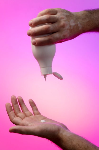 Free Photo hands holding hand cream over gradient background