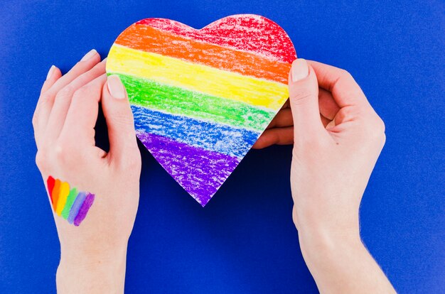 Hands holding a heart with pride day flag colors