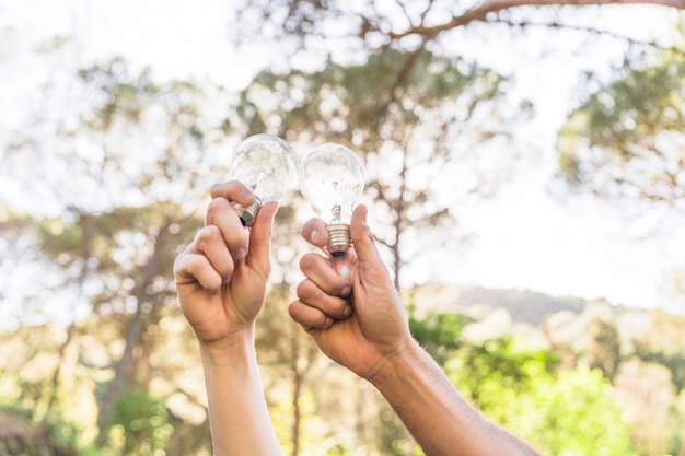 Free photo hands holding lamps against nature