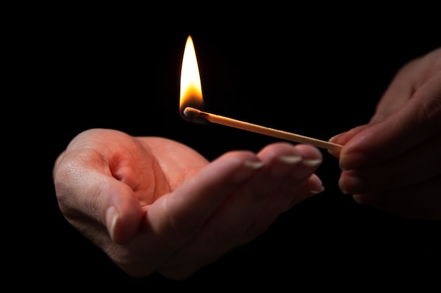 Hands holding lit matches low angle