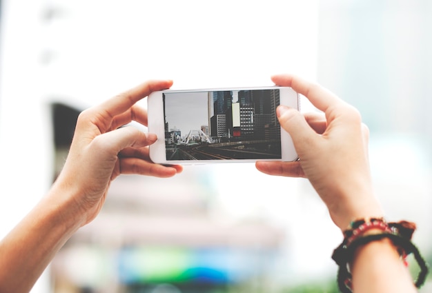 Hands holding mobile phone screen showing metro landscape city view photo