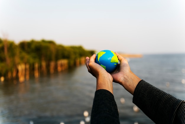 Free photo hands holding out a small globe