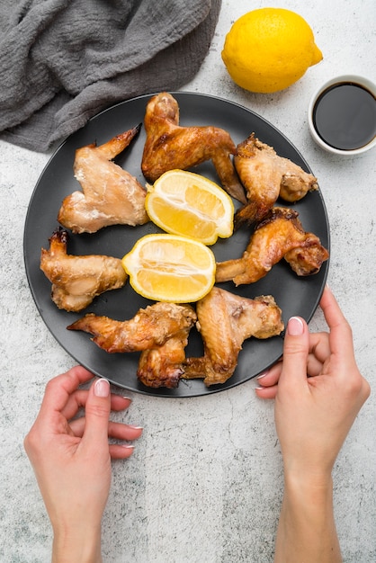 Free photo hands holding a plate with delicious kitchen wings