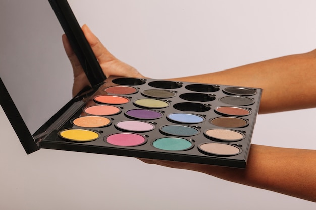 Free photo hands holding a set of multicolor eyeshadows