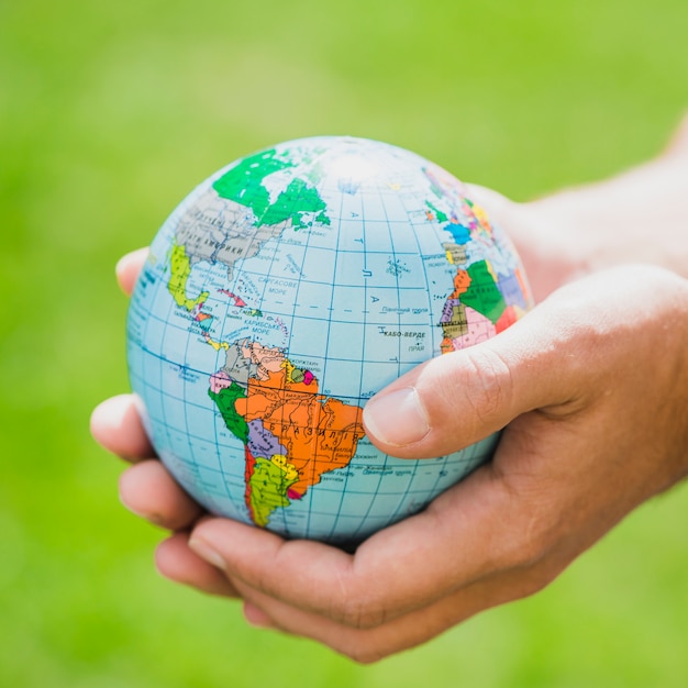 Free photo hands holding small globe against green background