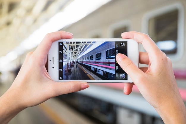 Free photo hands holding smartphone on platform near train