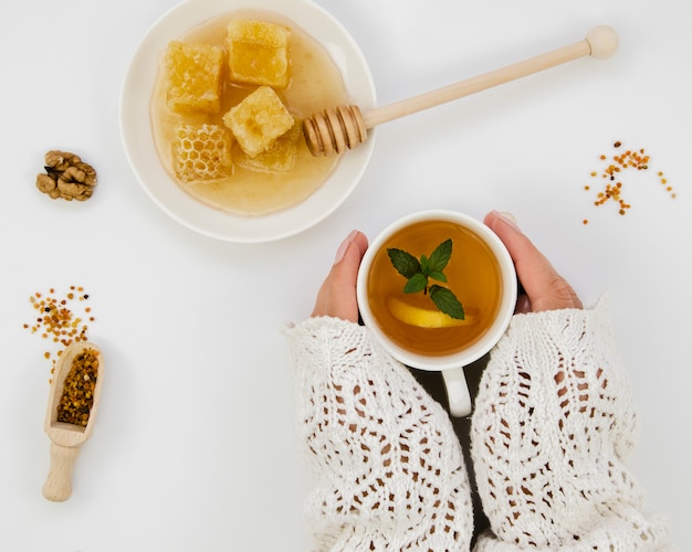 Hands holding tea with honey