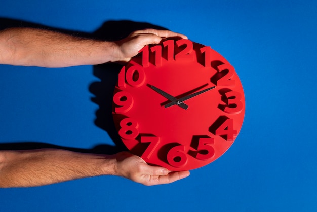 Free Photo hands holding wall clock still life