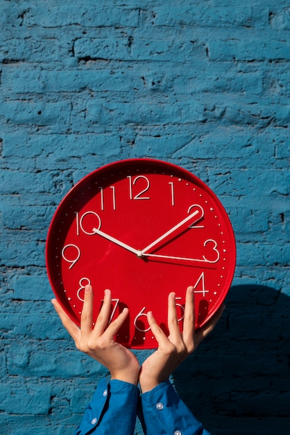 Free photo hands holding wall clock still life