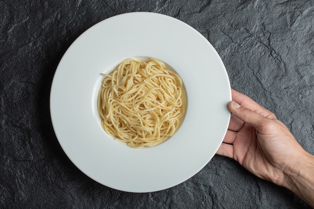 Free photo hands holding a white plate full of delicious noodles .