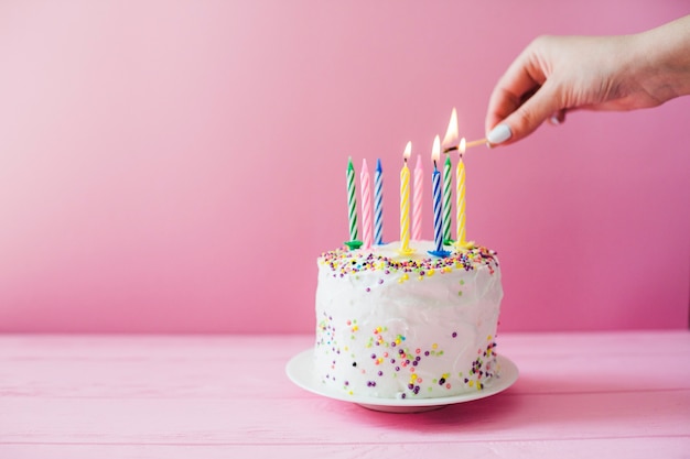 Hands lighting candles on cake