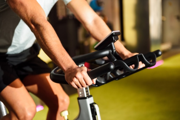 Hands of a man training at a gym doing cyclo indoor.