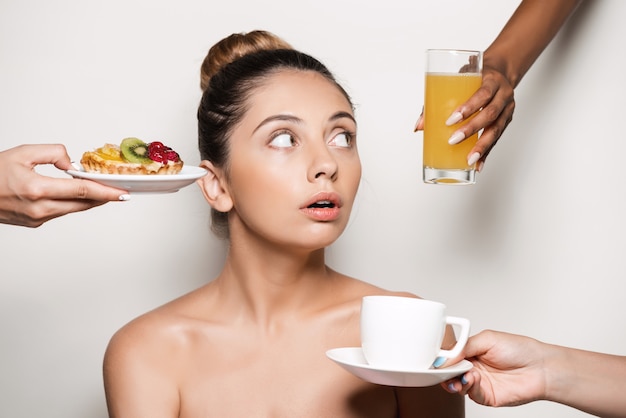 Hands offering cake and drinks to young beautiful woman