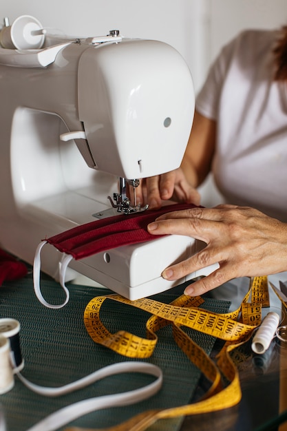 Hands of old woman sewing cloth face masks for friends