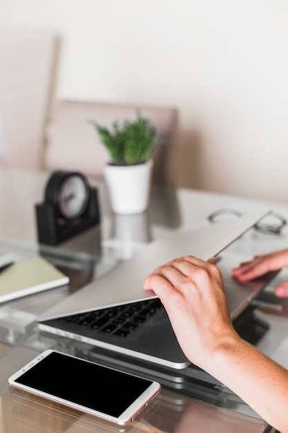 Hands opening laptop near smartphone on table