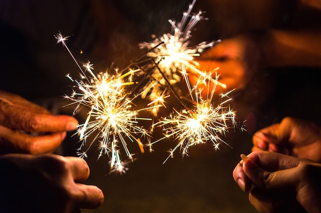 Hands of people holding sparkler, Bright festive Christmas sparkler.