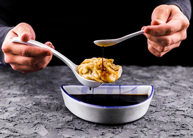 Hands pouring sauce on dumpling front view 