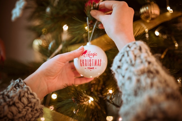 Hands putting ball on Christmas tree 