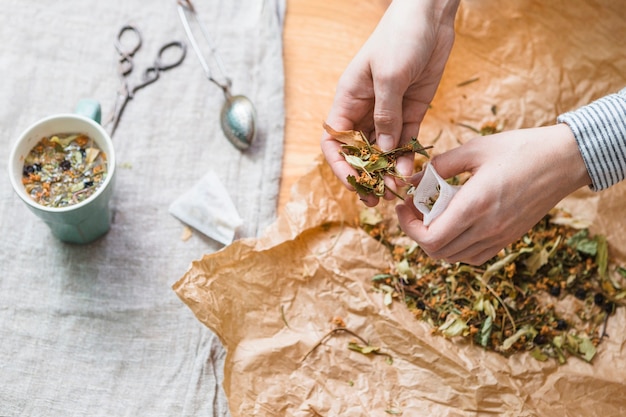 Free Photo hands putting herbal mixture into tea bag