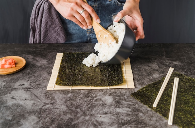 Hands putting rice on toasted seaweed