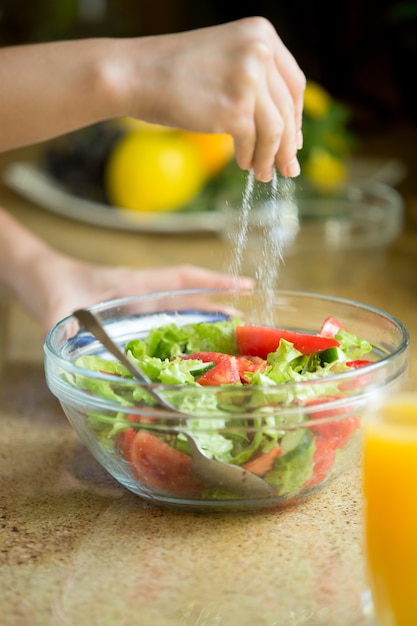 Hands salting a green salad