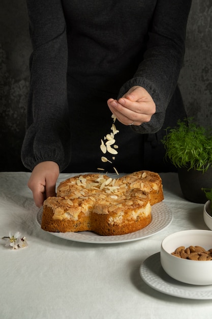 Hands sprinkling almonds on cake