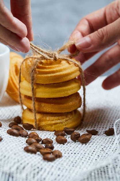 Free photo hands tying a stack of biscuits with coffee beans.