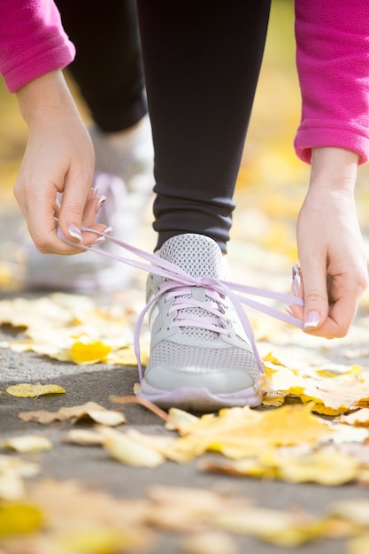 Free photo hands tying trainers shoelaces on the fall pave