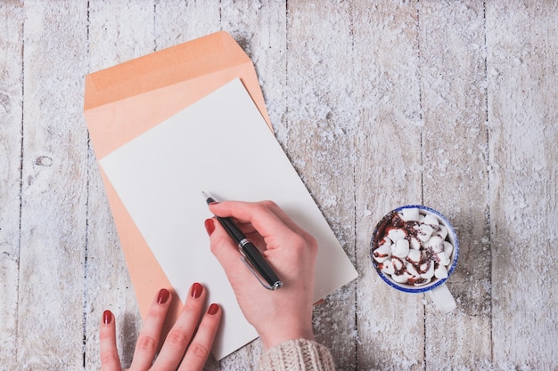 Hands typing on a paper with a cup next to it