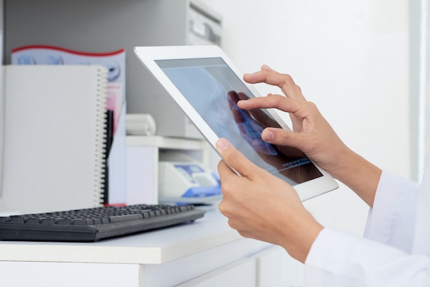 Free photo hands of unrecognizable female doctor looking at human skull x-ray on tablet