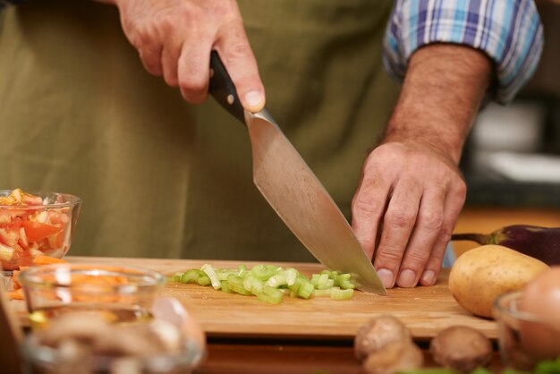 Hands of unrecognizable man cutting up fresh vegetables