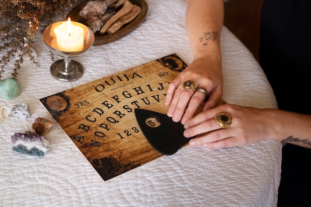 Free Photo hands using old wooden ouija board high angle