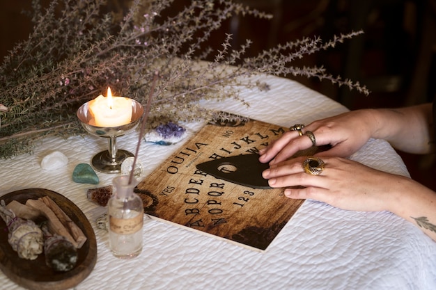 Free Photo hands using old wooden ouija board side view