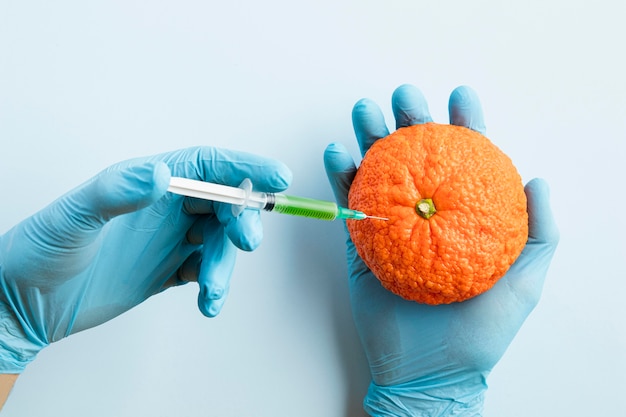 Hands wearing gloves and injecting chemicals in an orange