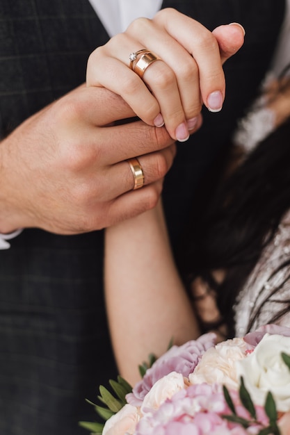 Free Photo hands of a wife and a husband with wedding and engagement rings and part of floral bouquet