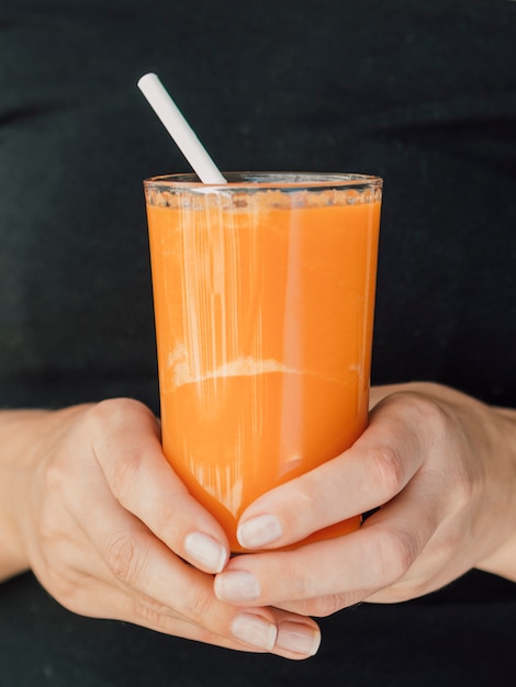 Free photo hands with carrot juice glass