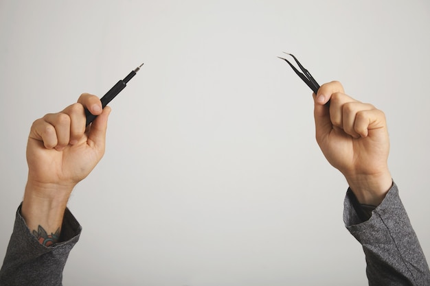 Hands with computer repair tools - screwdriver and pincers - raised up in the air