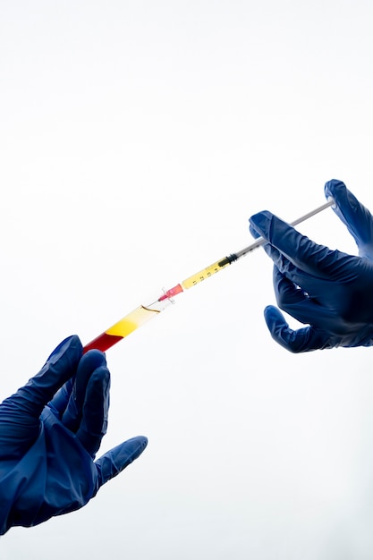 Hands with gloves wearing syringe and vial