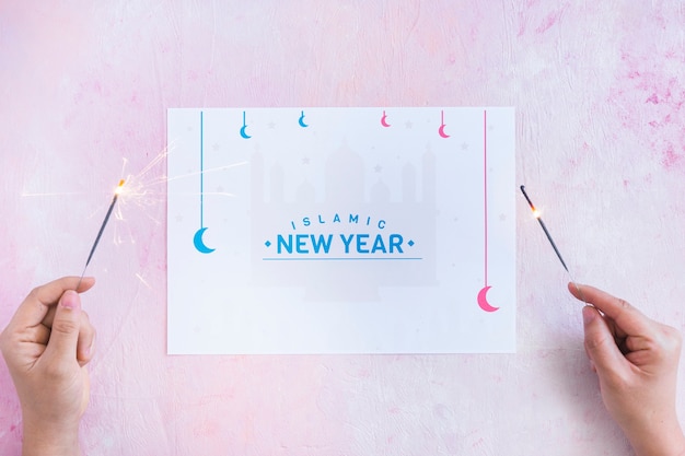 Free photo hands with sparklers and islamic new year words