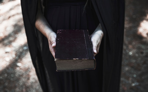 Free Photo hands of woman in black dress holding old book