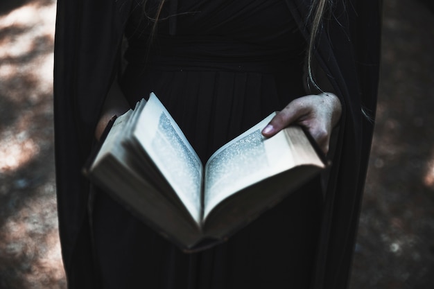 Free photo hands of woman in black dress holding opened book