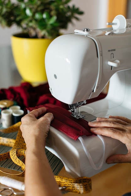 Free photo hands of a woman doing cloth face masks with sewing-machine