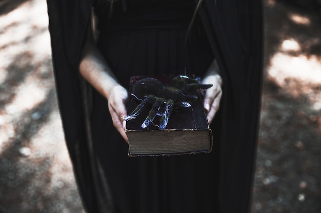 Free photo hands of woman holding book with spider on top