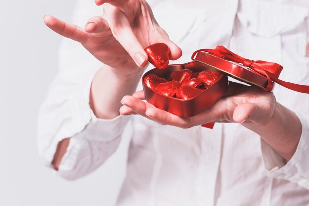 Hands of woman holding a box with red hearts