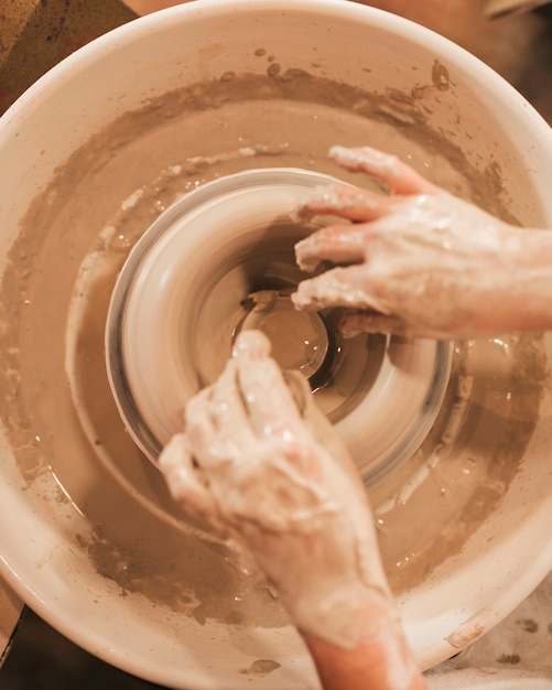 Free Photo hands of woman in process of making clay bowl on pottery wheel