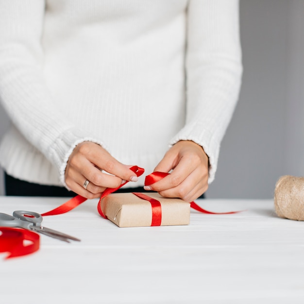 Hands wrapping present with red ribbon