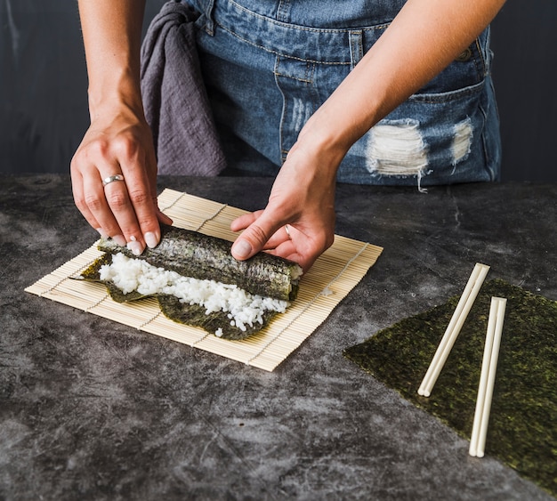 Hands wrapping toasted seaweed